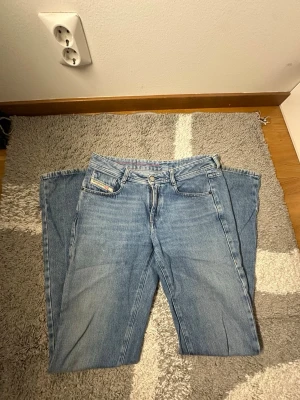 Blå  jeans från Diesel - Säljer ett par klassiska blå jeans från Diesel med rak passform och fem fickor. Jeansen har en snygg tvättad look och detaljer som Diesel Industry-märket på myntfickan. Perfekta till vardags för en avslappnad stil.