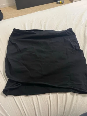 Svart kortkjol från H&M Divided - Enkel och stilren svart kortkjol från H&M Divided. Kjolen har en rak passform och är tillverkad i mjuk bomull, perfekt att matcha med en crop top eller hoodie. Snygg bas till garderoben för en avslappnad look.