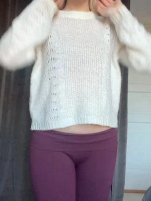 Vit stickad tröja med mönster - Mysig vit stickad tröja med snyggt hålmönster längs sidorna och rak passform. Tröjan har långa ärmar och ribbstickade muddar vid ärmslut och nederkant. Perfekt för lager-på-lager och chill dagar.