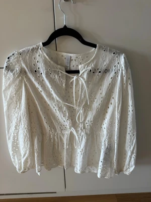 Vit broderad blus med knytband - Söt vit blus från New Yorker med broderade hålmönster och puffiga långärmar.