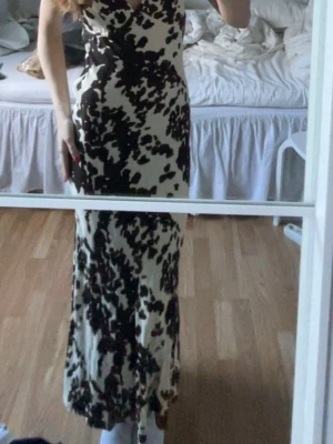 Långklänning - Jättefin långklänning med mönster. Justerbara band och har en dragkedja på sidan. Köpt från second hand💕Färgen är en blandning av brun och cremevit/beige.