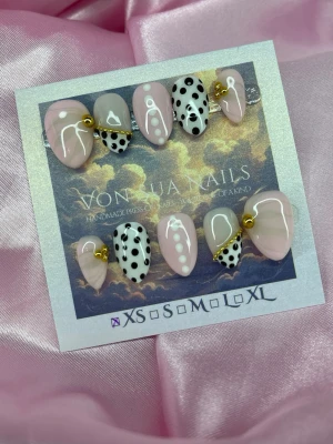 Bijou (XS);Short Almond - Snygga press-on naglar i mandelform från Vonlija Nails. Mix av ljusrosa, svartvita prickar och vita detaljer, samt guldfärgade kedjor som dekoration. Handgjorda och unika, perfekta för dig som vill sticka ut med cool design.