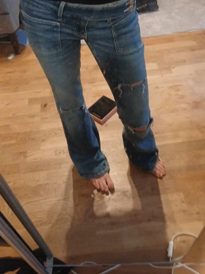 Blå slitna bootcut jeans stl s - Säljer ett par blå bootcut jeans med slitningar och hål på knäna. Jeansen är lowwaist och jätte snygga den enda lilla defekter är att dem har ett litet hål längst ner då dem var lite långa på mig förut men det är absolut inget som märks pris kan alltid diskuteras jeansen är i stl s från gina tricot