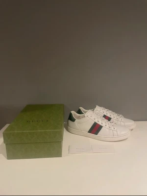 Gucci Ace  - Säljer nu ett par riktigt snygga Gucci Ace skor för riktigt bra pris. Skorna är i bra skick, men har tecken på användning. Inget som syns när de används. Original pris 8400kr. Storlek 41/5 Passar även 42 Hör gärna av er om ni har frågor.