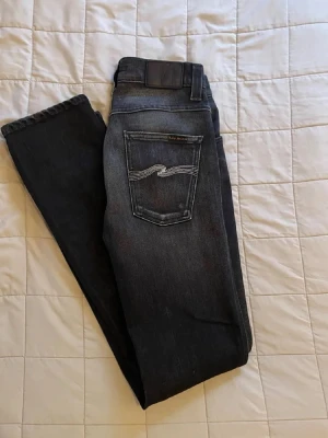 Mörkgråa Nudie Jeans - Säljer ett par mörkblå jeans från Nudie Jeans med raka ben och klassisk femficksmodell. Jeansen har snygga kontrastsömmar på bakfickorna och är tillverkade i slitstark denim. Perfekta för dig som gillar en stilren och tidlös look. W28 L32 passar mer som W29 