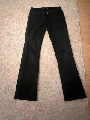 Svarta bootcut jeans LTB - Säljer ett par svarta bootcut jeans med klassisk femficksdesign och knappgylf. Jeansen har en lätt utsvängd passform nedtill och är perfekta för dig som gillar en tidlös look. Materialet är mjukt och stretchigt för extra komfort. Är från LTB storlek 36.