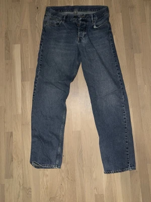 Blå raka jeans från Sweet SKTBS - Klassiska blå jeans från Sweet SKBTS med rak passform och fem fickor. Jeansen har en mörkblå tvätt och är tillverkade i slitstark denim. Liten reva vid bakfickan (se på sista bilden)