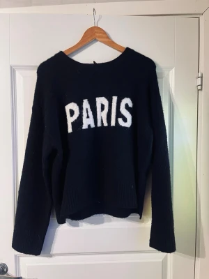 Mörkblå stickad tröja med PARIS-tryck - Jättefin mörkblå stickad tröja med ”PARIS” text framtill. Helt oanvänd och jag skulle säga att den är mer som en S/M i stoleken. Väldigt snygg och skönt material, skriv om ni undrar något!💙