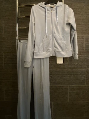 Ljusblå velour mjukissett från Gina Tricot  - Mysigt loungewear-set i ljusblå velour med zip-hoodie och matchande byxor. 