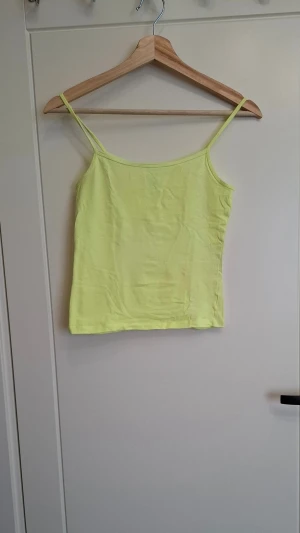 Gul linnetopp från Colin's XS - Snygg gul linnetopp från Colin's i storlek XS. Toppen har tunna axelband och är tillverkad i mjuk bomull, perfekt för varma dagar. Enkel och stilren design som är lätt att matcha med olika outfits.