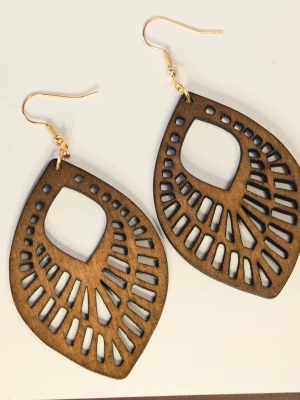 Ultralätta Bruna träörhängen - Unika örhängen i mörkbrunt trä från Stass med ett snyggt, laserutskuret mönster. De har en droppformad design och guldfärgade krokar som ger en cool och bohemisk vibe. Perfekta för dig som gillar naturmaterial och statement-accessoarer.