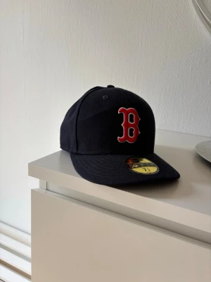 Boston Red Sox keps New Era navy - Snygg navyblå keps från New Era med Boston Red Sox-logga i rött och vitt framtill. Klassisk 59FIFTY-modell med böjd skärm och broderade detaljer. MLB-logga baktill och New Era-logga på sidan. Perfekt för dig som gillar sportig streetstyle.