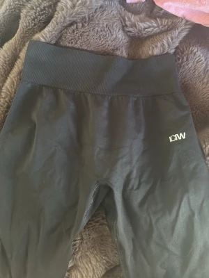 Svarta seamless leggings från ICANIWILL - Säljer ett par svarta seamless leggings från ICANIWILL med hög midja och ribbad linning. Stretchigt material som sitter skönt och formar sig efter kroppen. Perfekta för träning eller chill. Diskret ICW-logga på ena benet.