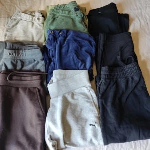 Mix av mjukisbyxor i olika färger - Säljer ett gäng mjukisbyxor i olika färger och modeller, perfekta för chill dagar. Färgerna inkluderar svart, grå, beige, brun, blå, grön och ljusgrå. Ett par är från Puma med logga på benet. Alla har resår i midjan och vissa har dragsko.