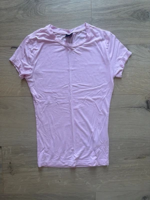 Ljusrosa t-shirt från Gina Tricot Xs - En basic ljusrosa t-shirt från Gina Tricot i mjuk bomull. Modellen har rund halsringning och korta ärmar. Perfekt att matcha med jeans eller kjol för en enkel och clean look. Sitter tight mot kroppen!