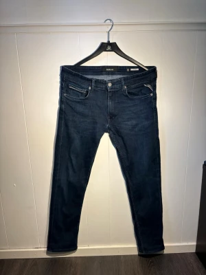Mörkblå grover från Replay - Mörkblå jeans från Replay, modell grover W32 L32, men uppsyda till L30 för bättre passform än L30 orginal. Jeansen har raka ben och är tillverkade i ett mjukt denimtyg som ger en skön passform. Perfekta nu inför sommaren under lite kyligare kvällar när shortsen inte vill på! 