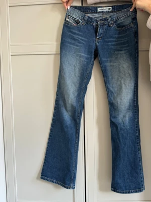 Blå bootcut jeans från Diesel - Säljer ett par as snygga blå bootcut vintage jeans från Diesel. De är perfekt låga i midjan och sitter åt runt rumpan men är utsvängda annars. Extremt snygga på alla! 