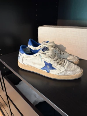 Golden Goose vita sneakers med blå detaljer - Golden Goose sneakers som ser riktigt fina ut men är rätt så använda. Inget större problem utifrån däremot så är det hål bak i hälen men ingenting man ser utan endast när man ej har på skorna. Priset kan diskuteras! Nypris 5400