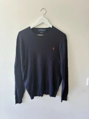 Mörkblå stickad Ralph Lauren tröja M - Jag säljer en mörkblå Ralph Lauren tröja. Den är i storleken Medium och har en väldigt bekvämlig textur på tyget vilket gör den till en lätt buren skön tröja.