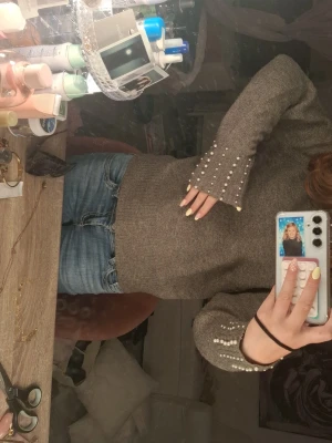Grön tröja med pärldetaljer - Snygg grön stickad tröja med pärlor längs ärmarna. Tröjan har en rak passform och vida ärmslut som ger en trendig look. Perfekt för dig som vill ha något extra till din outfit.