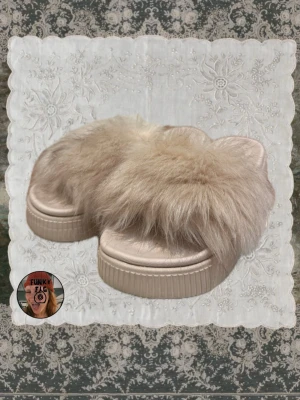Beige fluffiga platåtofflor - Säljer ett par beige tofflor med fluffig fuskpäls och platåsula. Tofflorna har öppen tå och bred rem med mjukt, lurvigt material som ger en trendig och cozy vibe. Perfekta för dig som vill ha något extra till din look.