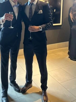 Mörkblå kostym - Hej, Jag säljer min marinblå Hugo Boss-kostym eftersom den tyvärr inte passar mig längre. Kostymen är i mycket fint skick och har endast använts vid två tillfällen. I paketet ingår allt som syns på bilden: Kavaj, Byxor, Skjorta, Skärp, Näsduk, Slips, Skor. På bilden är jag 190 cm lång och väger cirka 78 kg, vilket kan ge en uppfattning om passformen. Kvitto på kavajen och byxorna medföljer. Vid intresse eller frågor är du varmt välkommen att höra av dig