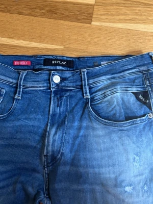 Blå jeans från Replay Myrflex - Säljer ett par blå jeans från Replay Myrflex med snygg tvätt och klassisk femficksmodell. Jeansen har normal midja, dragkedjegylf och Replay-logga på fickan. Perfekta för dig som gillar en avslappnad men trendig stil. Storlek 33 waist 34 Length 