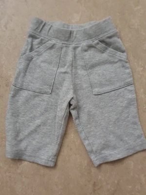 Shorts - Ett par gråa shorts i mjukt material med elastisk midja och två stora fickor framtill. Perfekta för en avslappnad stil och enkel att matcha med olika toppar.