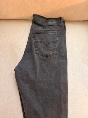 Levi's svarta high rise straight jeans - Snygga svarta jeans från Levi's i modellen 724 High Rise Straight. Jeansen har raka ben, klassisk femficksdesign och hög midja. Tillverkade i ett mjukt denimtyg som ger en skön passform. Perfekta för en trendig och avslappnad look.