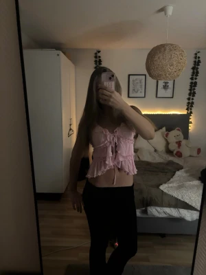 Rosa volangig linnetopp med knyt - Supersöt ljusrosa linnetopp med volanger och knyt framtill. Toppen har tunna axelband och är croppad med plisserat tyg. Perfekt nu till sommar och våren. ALDRIG ANVÄND