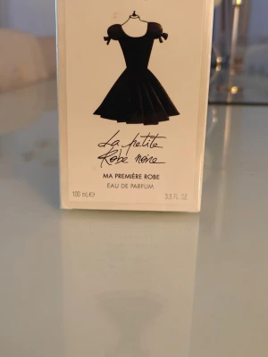 Guerlain La Petite Robe Noire EdP 100ml - La Petite Robe Noire Ma Première Robe Eau de Parfum från Guerlain i en elegant förpackning med svart klänning-illustration. Parfymen är på 100 ml och har en lyxig och feminin känsla, perfekt för dig som gillar klassiska dofter.