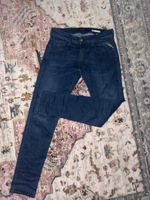 Mörkblå skinny jeans från Replay - Snygga mörkblå skinny jeans från Replay med klassisk femficksdesign och låg midja. Jeansen har en smal passform och är tillverkade i ett stretchigt denimtyg som ger en bekväm känsla. Perfekta för en trendig och avslappnad stil.