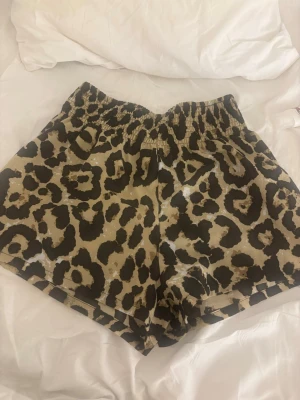 Leopardmönstrade shorts  - Snygga shorts med leopardmönster i beige och svart. De har en bekväm resår i midjan och är tillverkade i ett mjukt, lätt material som passar perfekt för varma dagar. Perfekta för dig som vill sticka ut lite extra.