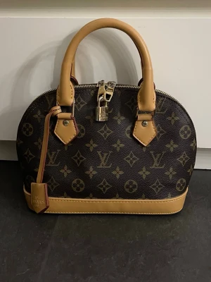 Louis Vuitton Alma BB - Louis Vuitton väska i modellen Alma BB (Ej äkta), men äkta läder. Använd fåtal gånger, inga defekter eller tecken på användning. Axelbandsrem medföljer🩷