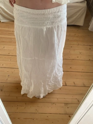Vit långkjol från Gina Tricot - Vit långkjol från Gina Tricot med smock i midjan och lätt, luftig känsla. Jag är 172 och kjolen är förkort för mig💕