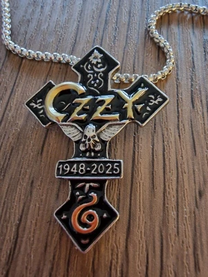 Halsband Ozzy Osbourne minnes - Halsband Ozzy minnes. Elegant tvåfärgat forntida egyptiskt kors och dödskalle 1948-2025. Inkl. kedja. Kedjans längd 60 cm. Berlock 4,8 cm hög. Bredd 3,5 cm.