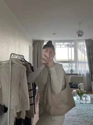 Beige axelväska  - Säljer en stilren beige axelväska i mjukt material med knutdetaljer på axelbandet, från Gina Tricot. Väskan har en slouchy form och är perfekt för dig som gillar minimalistisk design. Passar till många olika outfits och är enkel att bära över axeln.