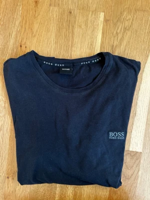 Svart t-shirt från Hugo Boss  - Svart t-shirt från Hugo Boss med diskret logga på bröstet. Klassisk rund halsringning och korta ärmar. Tillverkad i mjuk bomull som känns skön mot huden. .