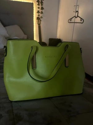 Limegrön handväska från SWEETSA - Trendig limegrön handväska från SWEETSA i slätt konstläder. Jättefin och perfekt om du har en diskret outfit men vill poppa lite med färg. Perfekt tillbaka tillfällen. Bra skick knappt använd och den säljs inte i butik längre så passa på!
