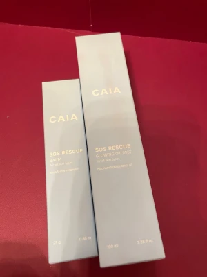 CAIA SOS Rescue Balm & Oil Mist - Två produkter från CAIA: SOS Rescue Balm med sheasmör och vitamin E samt SOS Rescue Glowing Oil Mist med niacinamid och blue tansy oil. Båda passar alla hudtyper och kommer i ljusblå förpackningar. Perfekt för dig som vill boosta din hudvårdsrutin.