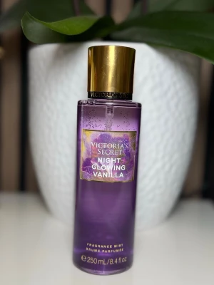 Victoria's Secret Night Glowing Vanilla - En lyxig parfymmist från Victoria's Secret i doften Night Glowing Vanilla. Flaskan är lila med guldigt lock och detaljer, rymmer 250 ml. Perfekt för dig som älskar söta och varma vaniljtoner.