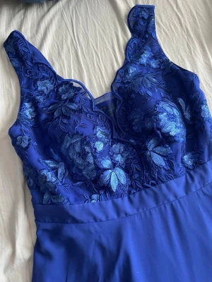 Royalblue balklänning - Royalblue balklänning/aftonklänning/maxiklänning med spets och broderidetaljer från bonprix, bpc collection.  Helt ny och oanvänd med prislapp. Färg: kungsblå/royalblue. Det finns insydda kupor i bysten. Resår i ryggen,mycket stretchig! Mått: - Byst: cirka 75 cm men väldigt stretchig. - Midja: cirka 65-70 cm. - Längd från armhålan och ner: cirka 120 cm. 