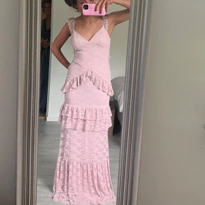 Ljusrosa långklänning med volanger och spets - Såå fin rosa bal klänning , med öppen rygg och super fina detaljer. Personen på bilden är 163 och på bild har hon inga skor🩷den är i storlek S som är slutsåld på hemsidan 🩷🩷🥰tveka inte om att fråga om mer bilder !! Vissa små defekter längst ner på klänning ( att den är lite sliten efter som den har ju andvänt en gång men kan skicka bild så får ni avgöra ❤️
