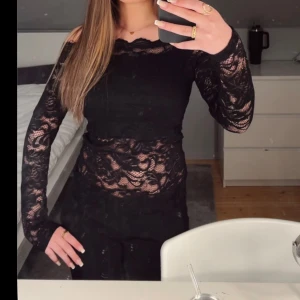 Svart spetsblus med lång ärm - Säljer en svart blus i genombruten spets med lång ärm och rundad halsringning. Blusen har en figurnära passform och transparenta partier som ger en snygg look. Perfekt att styla med jeans eller kjol.