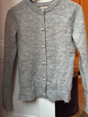 Grå kofta med pärlknappar - Mysig grå kofta som passar perfekt nu till våren. Den är nopprig därav priset. Den har superfina pärlknapppar och är från Holly & White by Lindex. Teveka inte att höra av dig om du har frågor och kika gärna in mina andra annonser! 💕📬