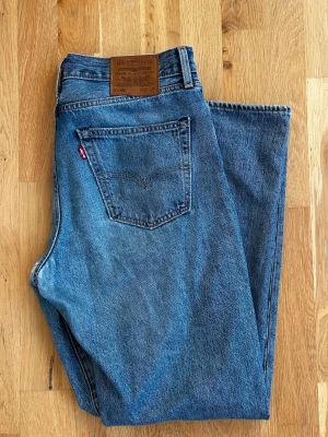 Blå raka jeans från Levi's 568 (Storlek W32 L34) - Säljer ett par klassiska blå jeans från Levi's med rak passform och femficksdesign. Jeansen har normal midja och är tillverkade i slitstark denim.