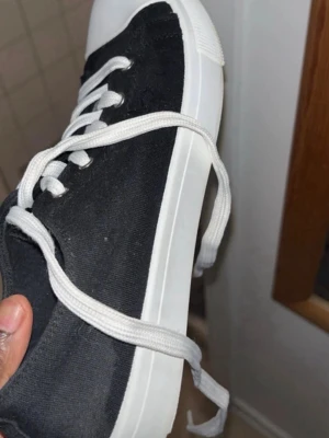 Svarta sneakers  - Säljer ett par snygga svarta sneakers med vita snörningar och vit tå. Skorna är bekväma och passar perfekt till vardagsbruk. Det finns några tecken på användning,mindre  Inget som påverkar funktionen, och det går enkelt att fräscha upp med rengöring. GÅR ATT DISKUTERA PRIS❗️‼️‼️ storlek 37