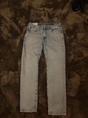 Ljusblå raka jeans - Säljer ett par ljusblå jeans med rak passform och klassisk femficksdesign. Jeansen har normal midja och är tillverkade i denim. Perfekta för en avslappnad och trendig stil.