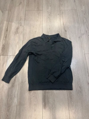 Långärmad pikétröja Massimo dutti  - Snygg mörkgrön pikétröja från Massimo Dutti med lång ärm och krage. Tröjan har knäppning med två knappar vid halsen och ribbade muddar vid ärmslut och nederkant. Perfekt för en stilren och enkel look.