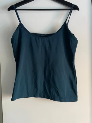 Mörkblå linnetopp med smala band - En enkel och stilren mörkblå linnetopp med tunna axelband och rak passform. Stretchig. Saknar storleksetikett men känns som L. 